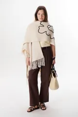 Ruana color marrón con flecos y bordados en el contorno.