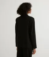 Blazer negro de poliéster y viscosa, de corte alargado, con cuello solapa, manga larga, doble botón frontal y bolsillos con solapa.