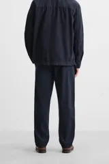 Pantalón azul marino de corte recto, confeccionado en tejido de algodón y lino. Tiene cintura elástica ajustable con cordón, bolsillos delanteros y traseros de vivo. Cierre frontal con cremallera y botón.