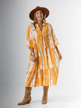 Vestido midi de corte amplio con estampado abstracto en tonos azules, blancos y beige. Tiene cuello en V, mangas 3/4 con volados y corte escalonado en la falda.