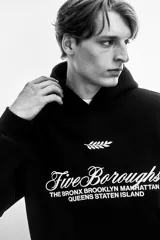 Canguro negro con capucha de doble capa, hombros caídos, diseño estampado con texto "Five Boroughs" y bolsillo canguro.