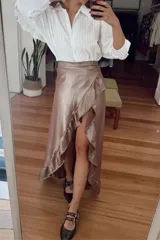 Falda larga color verde metálico, con volado en cascada y tajo frontal. Corte cruzado.