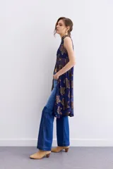Camisa larga sin mangas confeccionada en viscosa azul con estampado de flores doradas y cuello mao. Presenta bordados en cuello y cartera frontal, y cierre frontal con cremallera.