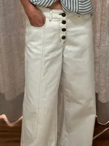 Pantalón ancho de denim con diseño patchwork en diferentes tonos de azul, con tiro alto, corte holgado y cierre frontal con botones.