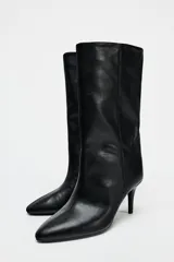 Bota de cuero sintético color negro, con caña media de efecto arrugado, punta fina y tacón fino.