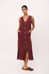 Vestido largo sin mangas, color rojo vibrante, con escote en V y cierre de botones frontal. Presenta tajos laterales y un pequeño aplique bordado de cerezas en el pecho.