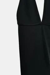 Top de color fucsia con escote pronunciado en V y cuello halter. Presenta una costura horizontal que marca la transición entre el busto y el torso.