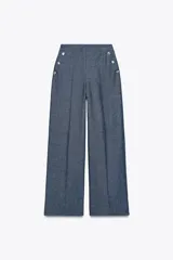 Pantalón ancho azul de tiro alto confeccionado en lino, con bolsillos delanteros con falsos botones y cierre lateral con cremallera oculta.