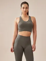 Top deportivo gris oscuro con espalda deportiva y banda elástica en el bajo busto.