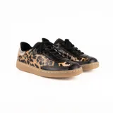 Zapatillas bajas de cuero con estampado animal print, puntera y cordones negros, contrafuerte dorado y suela color caramelo.