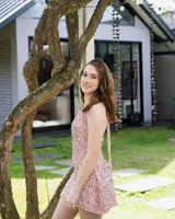 Vestido corto color fucsia con escote en V, breteles finos que se atan al cuello, corte a la altura de la cadera y falda acampanada con ruedo irregular.