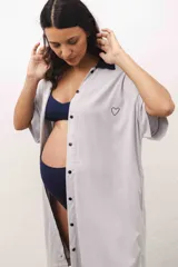 Camisa maternal gris claro de viscosa suave, con cuello camisero azul marino, cierre frontal con botones, mangas cortas y bolsillo lateral.