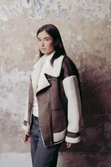 Campera oversized en textil tipo piel vuelta y corderito sintético, con cuello alto y hebillas.