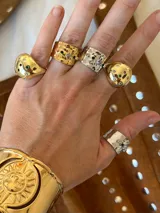 Anillo dorado con forma irregular y piedras de colores incrustadas.