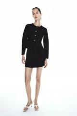 Chaqueta negra de punto fino con cuello redondo, manga larga, corte peplum y cierre frontal con botones joya.