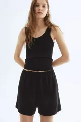 Short negro de corte holgado con tiro alto, cintura elástica fruncida y bolsillos laterales discretos.