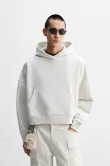 Sudadera color crudo, estilo hoodie, corte boxy, con capucha, manga larga, bolsillo tipo canguro y terminaciones en rib.