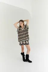 Chaleco tejido de lana con patrón de rombos en tonos lila, rojo y beige, con cuello en V y ribetes en color crema. Diseño oversize.