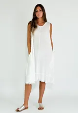 Vestido blanco de lino y algodón, corte suelto, sin mangas y largo midi con terminación desflecada.