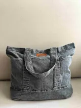 Bolso tote grande de jean gris con asas de mano y laterales con bolsillos.