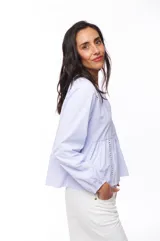 Blusa celeste a rayas verticales con escote en V, mangas largas y botones frontales.