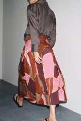 Falda midi de tiro alto confeccionada en hilatura de algodón con estampado geométrico multicolor. Detalle de pliegues en cintura y bajo evasé. Cierre con cremallera oculta en costura.