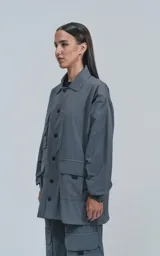 Campera gris con broches en el delantero, forrada con red, múltiples bolsillos con detalles en réflex y puños elásticos en las mangas. Confeccionada en textil liviano 100% poliéster y calce oversize.