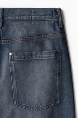 Pantalón de jean azul oscuro de corte holgado, con tiro bajo, cinco bolsillos y pierna extra ancha con pliegues en el tobillo.