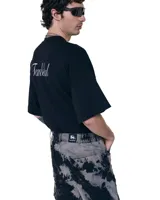 Short unisex de denim 100% algodón con acabado overo (manchado). Tiro medio, calce relajado y largo medio sobre la rodilla. Dobladillo con franja más oscura y bolsillos amplios.