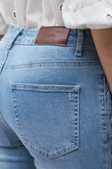 Jean de mezclilla azul medio, corte oxford o bota ancha, tiro medio/alto, con costura central marcada en el frente de ambas piernas.