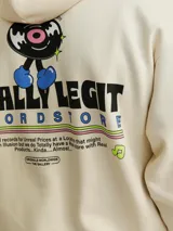 Hoodie color crema con capucha y manga larga, de corte holgado y estampado frontal con un personaje de caricatura y la frase "Totally Legit".