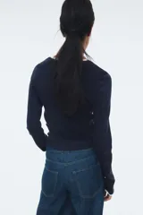 Buzo de manga larga color azul marino, de tejido de punto acanalado y corte ajustado. Presenta cuello redondo y puños con ribete blanco contrastante.