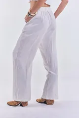 Pantalón de lino color beige, de corte recto y tiro alto, con cierre de botón y cremallera.