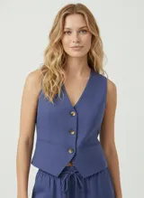 Chaleco sastrero azul con escote en V, cierre frontal con botones y bolsillos laterales. Confeccionado en lino y viscosa, de tejido ligero y elegante.