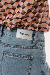 Minifalda de jean azul claro con corte evasé, detalle de short interno y cinturón negro con argollas metálicas.