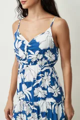 Vestido corto de color negro con tirantes finos y escote en V. Presenta un detalle fruncido en el pecho, cintura elastizada y falda con un volante en el bajo.