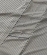 Remera deportiva de manga corta y cuello redondo, color beige claro, con textura acanalada vertical. Presenta detalles reflectantes en los hombros.