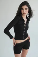 Camisa negra de lycra de algodón con cuello clásico, mangas largas y cierre frontal con hilera de ganchos metálicos.