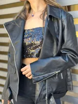 Chaqueta negra estilo motociclista de cuero sintético con cierre asimétrico y cuello con solapas.