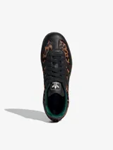 Championes Adidas Samba OG con estampado de guepardo, detalles en cuero negro, forro interior verde y suela marrón. Zapatilla de corte bajo con cordones negros y las tres tiras características de Adidas en cuero negro.