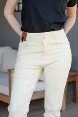Pantalón jean negro de tiro alto, con cinco bolsillos, confeccionado en tela con elastano. Tiene cierre frontal con doble botón y cierre metálico, y detalle de cuero en la parte delantera de la pretina.