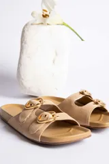 Sandalias de cuero color beige con dos tiras anchas y hebillas doradas ajustables.