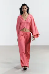 Pantalón de tiro alto color rosado, confeccionado en hilatura con lino, de pierna ancha y cintura elástica ajustable con cordones.