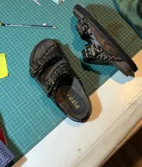 Sandalias de cuero color marrón con dos tiras anchas con hebillas metálicas y ojalillos.