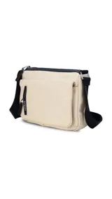 Bandolera color beige de nylon, con correa negra regulable. Tiene un bolsillo delantero con tapa, dos bolsillos internos (uno con cierre) y un bolsillo trasero.