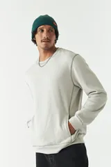 Buzo de felpa color gris claro, con cuello redondo, mangas largas y costuras a contratono. Presenta lettering estampado en el pecho, bolsillos laterales y logo en grifa de goma.