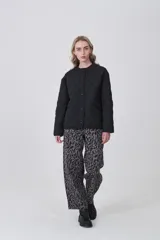 Campera acolchada negra, con diseño capitoné en rombos, cuello redondo y cierre frontal con botones a presión. Posee bolsillos delanteros amplios.