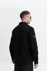 Sobrecamisa color marrón claro de twill de algodón, con cuello clásico, cierre frontal con botones a tono, dos bolsillos de parche con solapa abotonada en el pecho y mangas largas con puños abotonados.