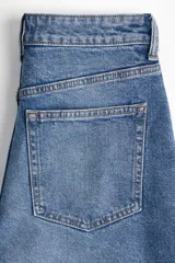 Pantalón de jean azul de corte ancho, tiro alto y largo tobillero. Cuenta con cinco bolsillos, cierre con cremallera y botón.