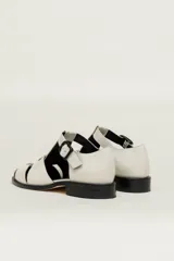 Sandalia roja de cuero vacuno con diseño de tiras entrecruzadas y hebilla lateral. Tiene suela de cuero artesanal y taco bajo.